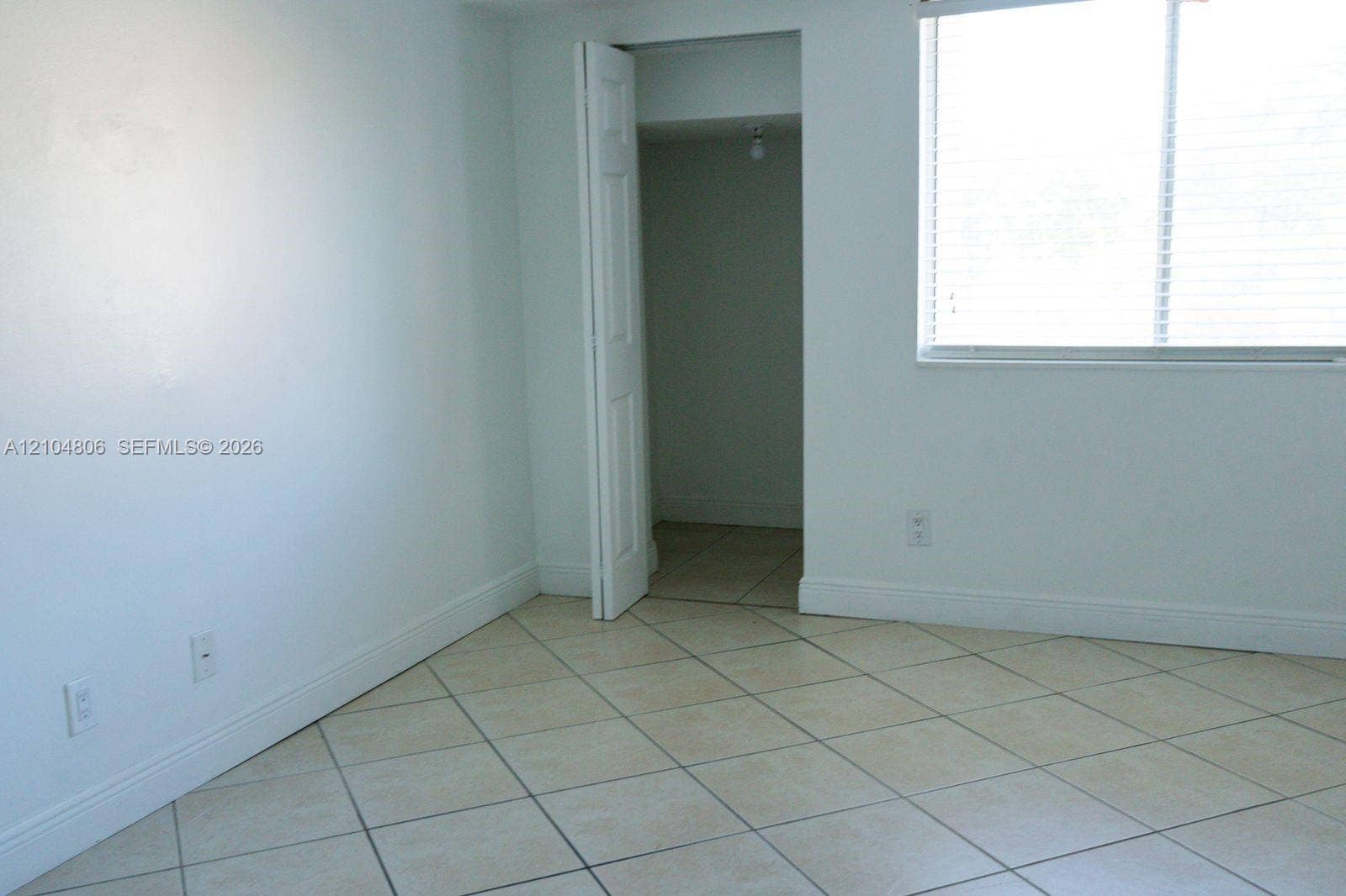 10451 SW 157th Place, #303, Miami, FL 33196 Neutral-toned tile flooring, white walls, and a window with blinds