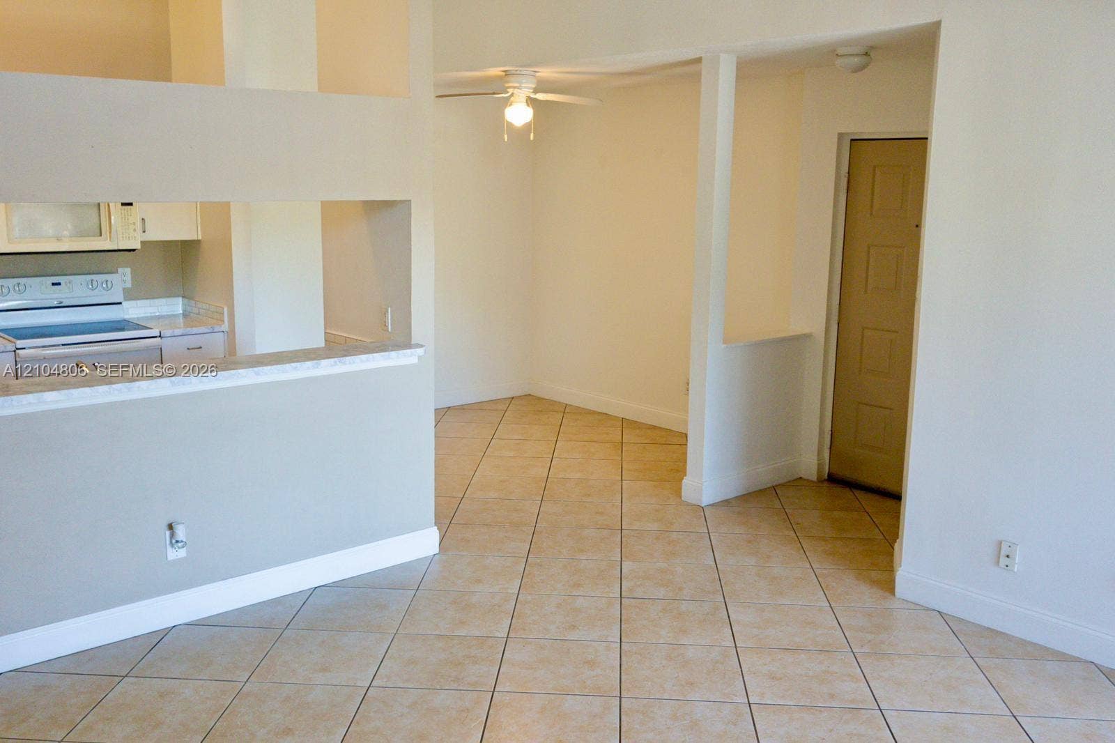 10451 SW 157th Place, #303, Miami, FL 33196 Open concept layout with neutral tile flooring, a kitchen pass-through, a ceiling fan, and a light-toned interior door