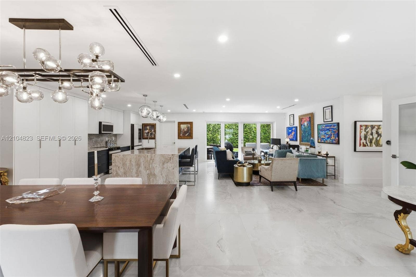 291 E Shore Drive E, Miami, FL 33133 Open-concept living space featuring wood-finish dining table, a large kitchen island with a stone finish, recessed lighting, and expansive glass doors