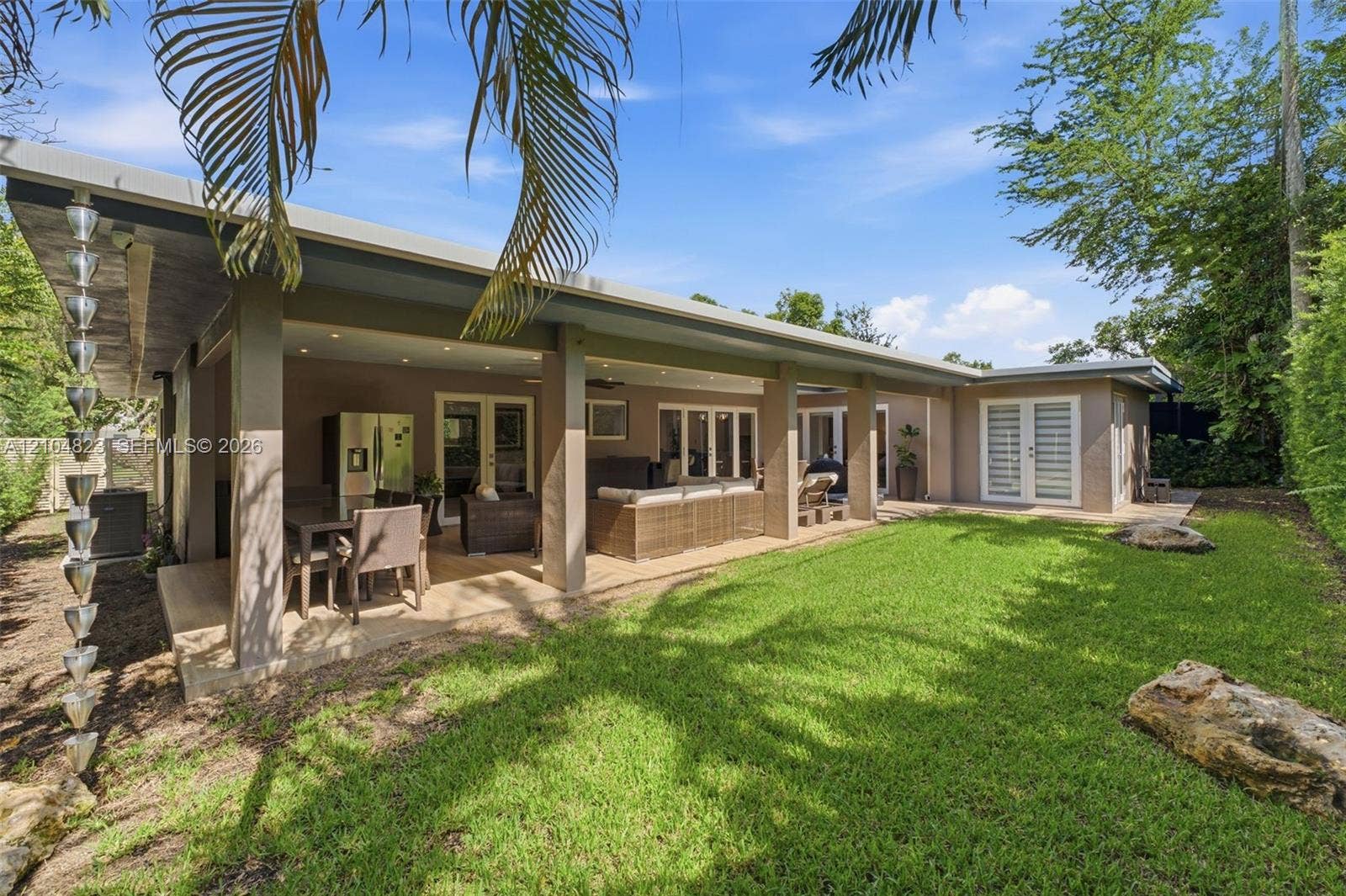 291 E Shore Drive E, Miami, FL 33133 Expansive rear patio with recessed lighting and exterior ceiling fan, featuring a rain chain downspout and multiple glass panel doors