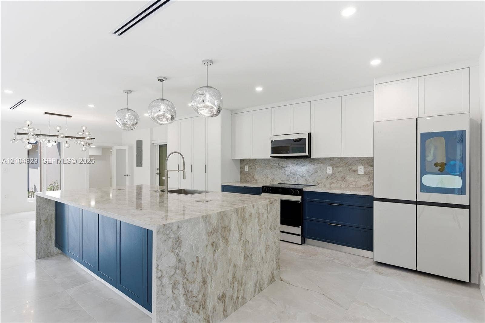 291 E Shore Drive E, Miami, FL 33133 Kitchen featuring a large central island with waterfall-edge stone countertops, two-tone cabinetry, stainless steel appliances, and pendant lighting