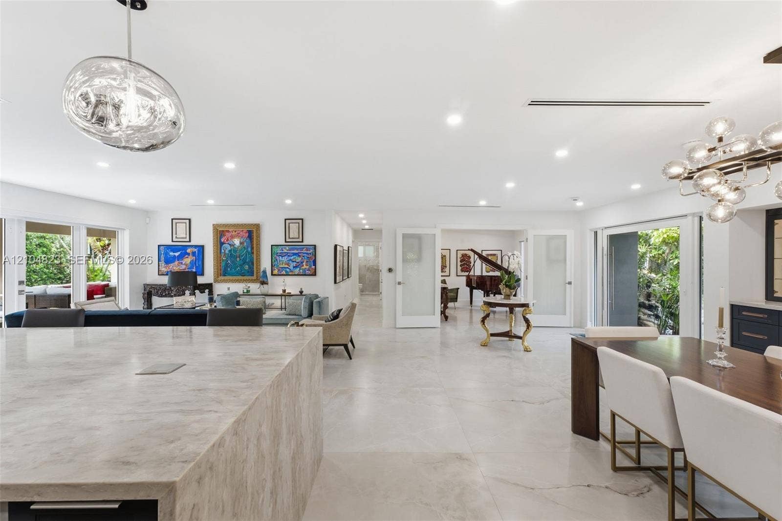 291 E Shore Drive E, Miami, FL 33133 Recessed lighting throughout, wide plank tile flooring, expansive sliding glass doors, built-in cabinetry, and a contemporary chandelier