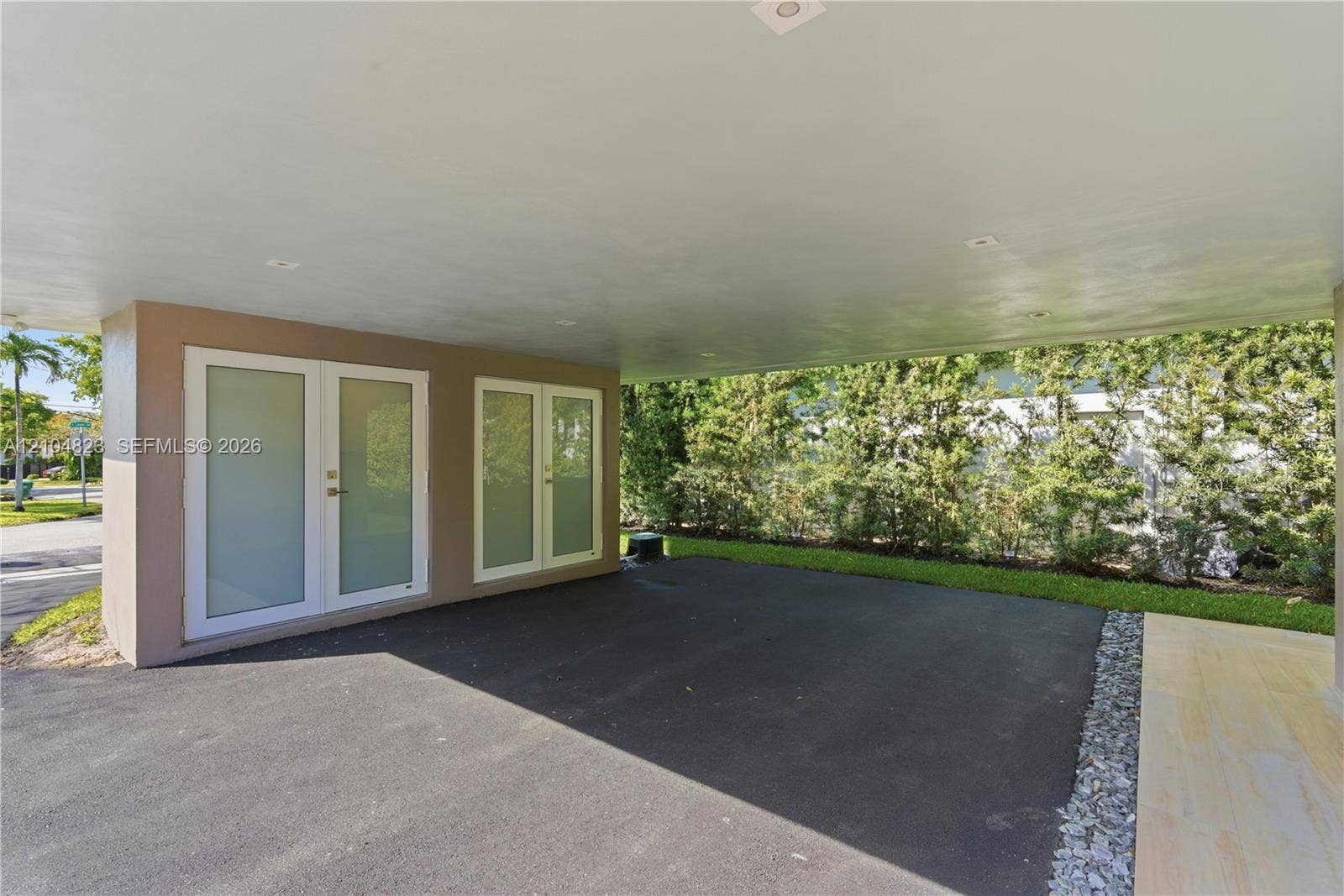 291 E Shore Drive E, Miami, FL 33133 Covered parking area with recessed lighting, double-door entry, additional fixed windows, and a privacy hedge