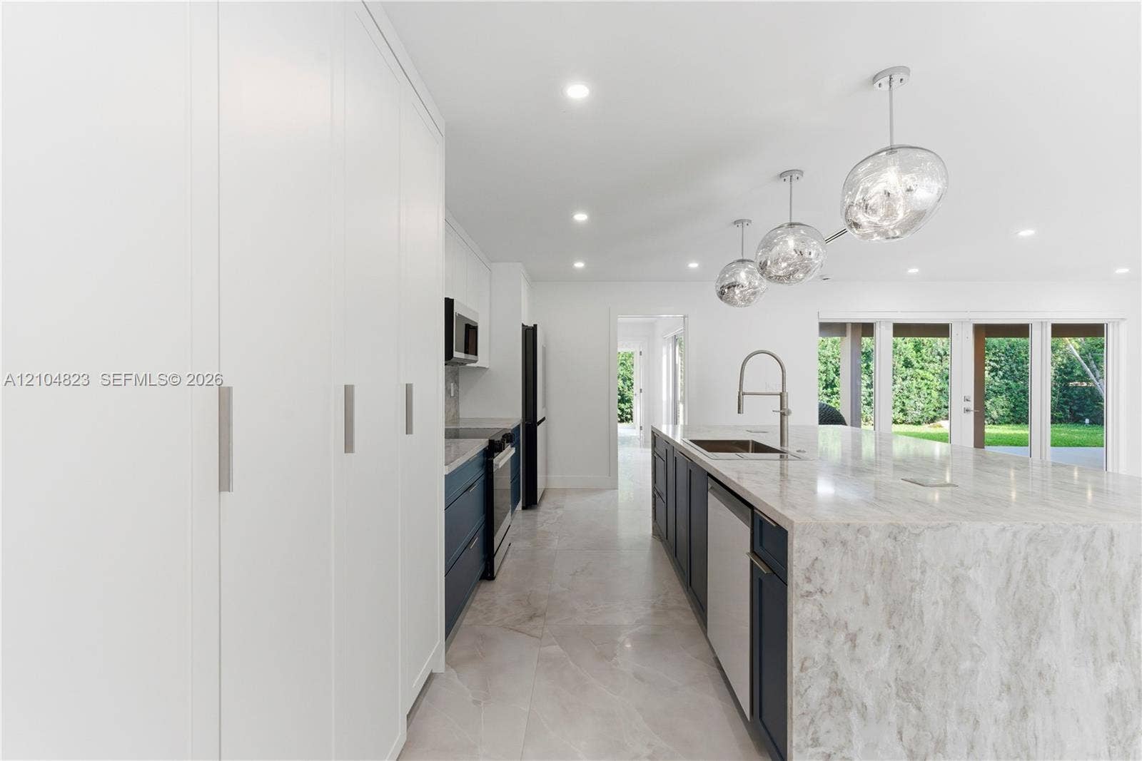 291 E Shore Drive E, Miami, FL 33133 Kitchen featuring floor-to-ceiling cabinetry, a stone-top waterfall island, modern pendant lighting, deep-toned base cabinetry, and large-format tile flooring