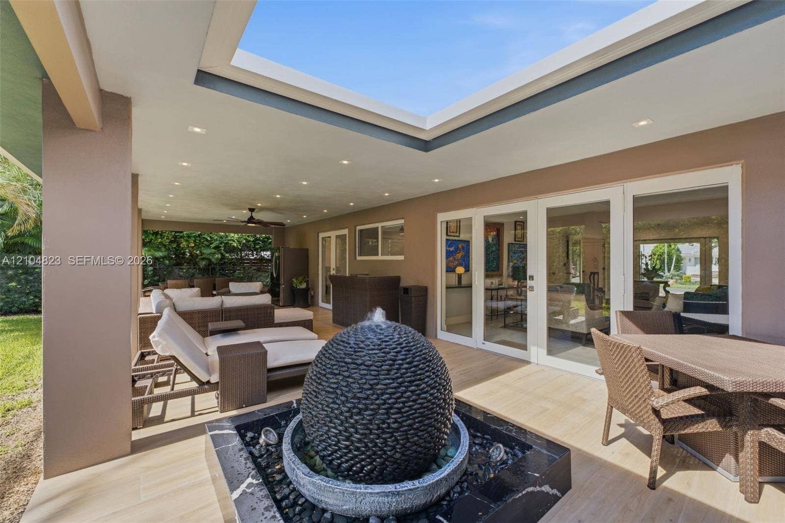 291 E Shore Drive E, Miami, FL 33133 Expansive covered patio featuring an integrated fountain, recessed lighting, and multiple sets of glass panel doors