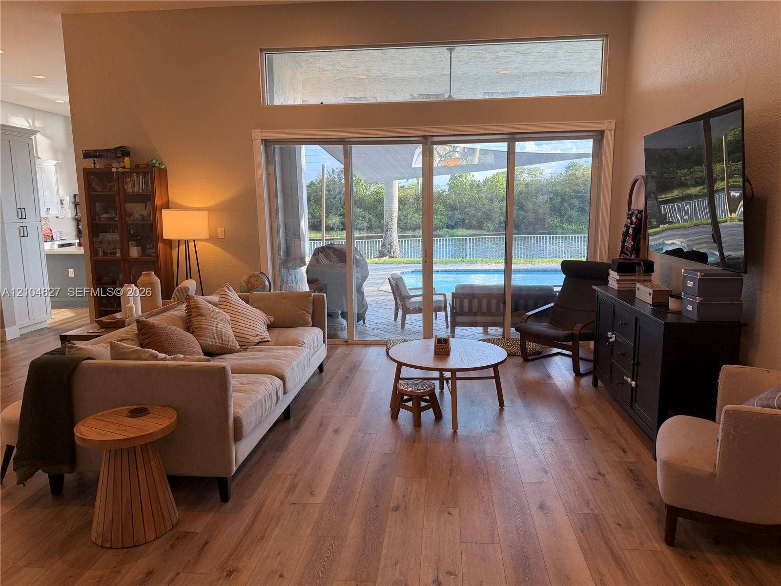 Wood-finish flooring throughout, vaulted ceiling, and sliding glass doors to outdoor patio with pool