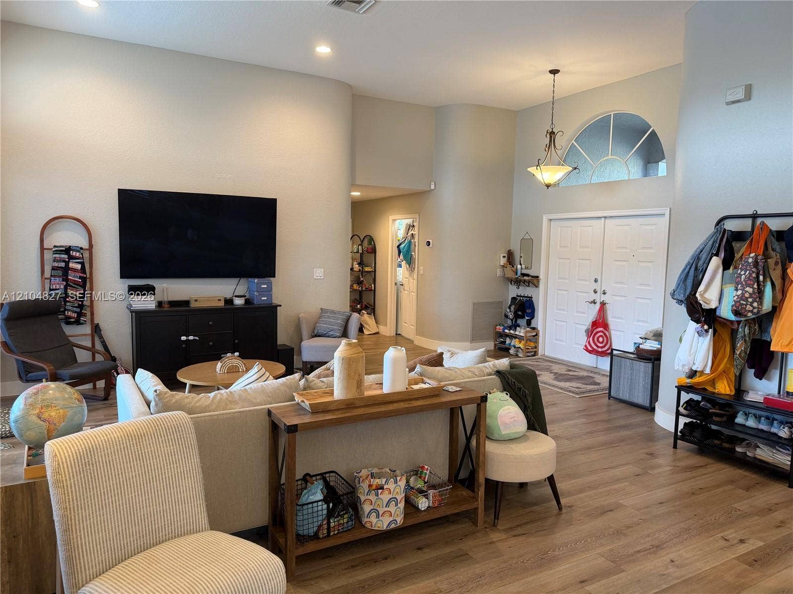 Vaulted ceiling with recessed lighting, wood-finish flooring, double front entry doors, and a decorative arched window