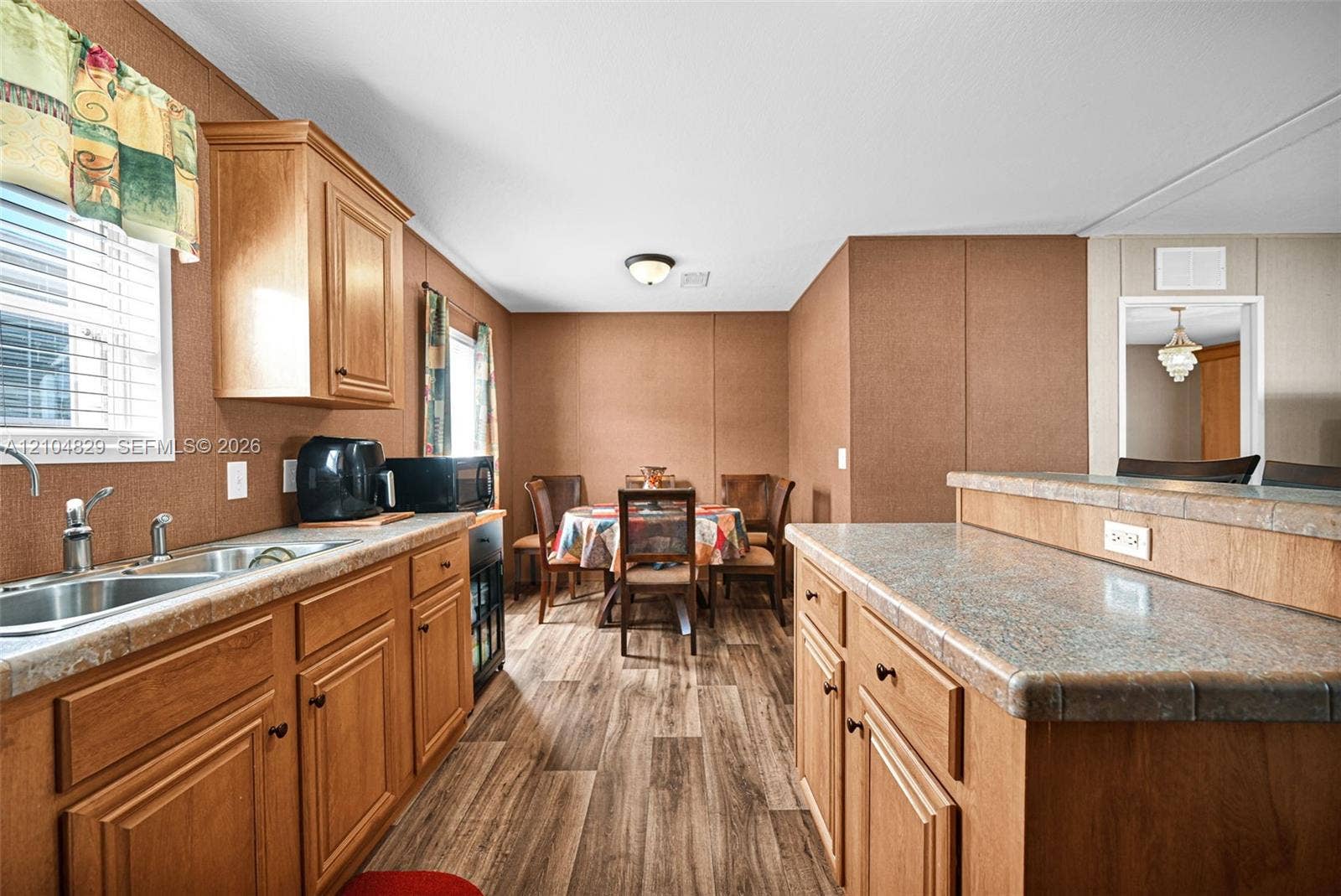 1880 SW 83rd Terrace, Davie, FL 33324 Kitchen area featuring wood-finish cabinetry, laminate countertops, a dual-basin sink, and wood-finish flooring
