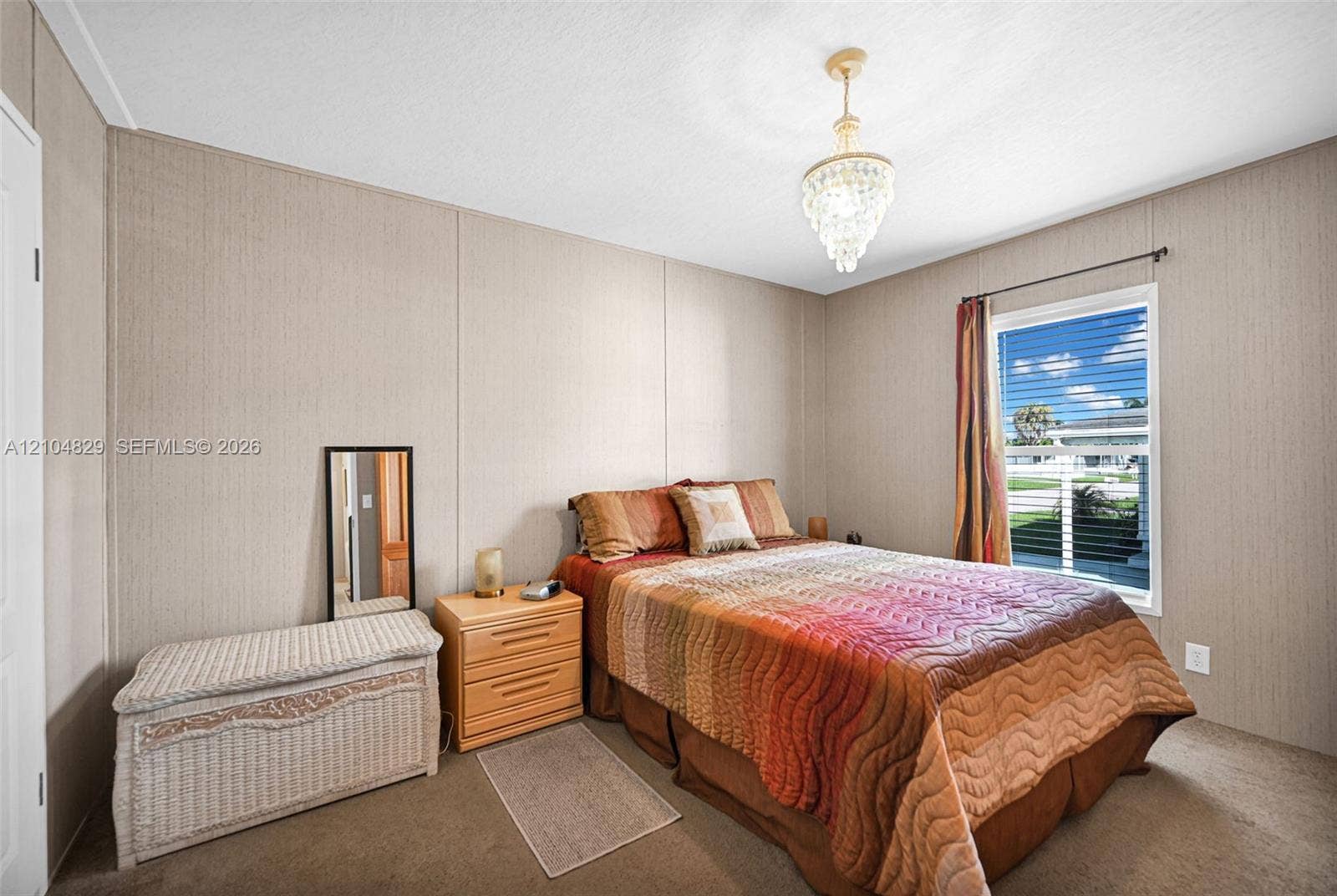 1880 SW 83rd Terrace, Davie, FL 33324 Room featuring neutral wall paneling, wall-to-wall carpeting, an elevated window, and a multi-tiered crystal pendant light fixture