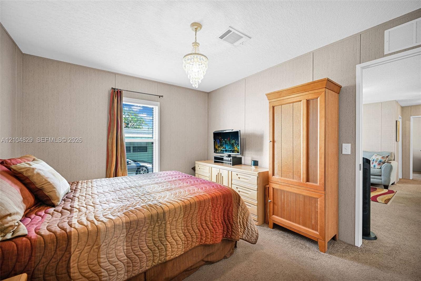 1880 SW 83rd Terrace, Davie, FL 33324 Neutral-toned interior walls featuring vertical paneling, neutral carpeting, and a crystal-style chandelier fixture