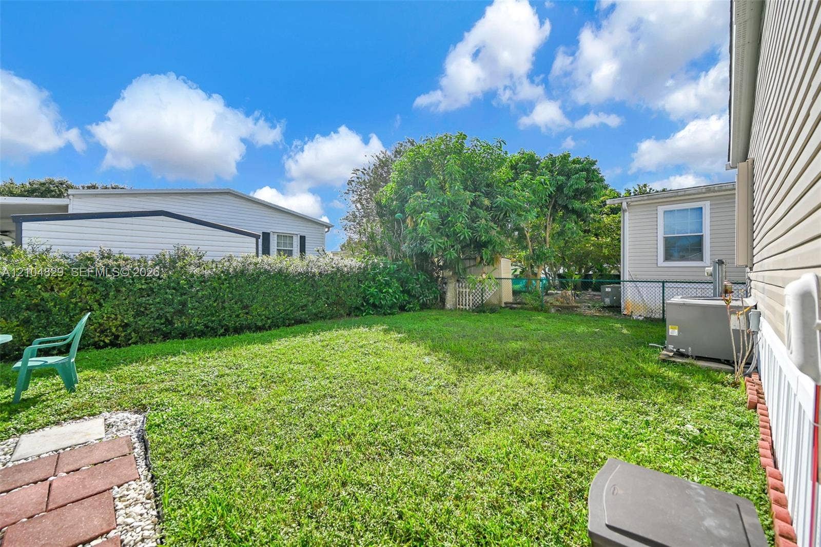 1880 SW 83rd Terrace, Davie, FL 33324 Side yard featuring a grass lawn, perimeter shrubbery, and chain-link fencing