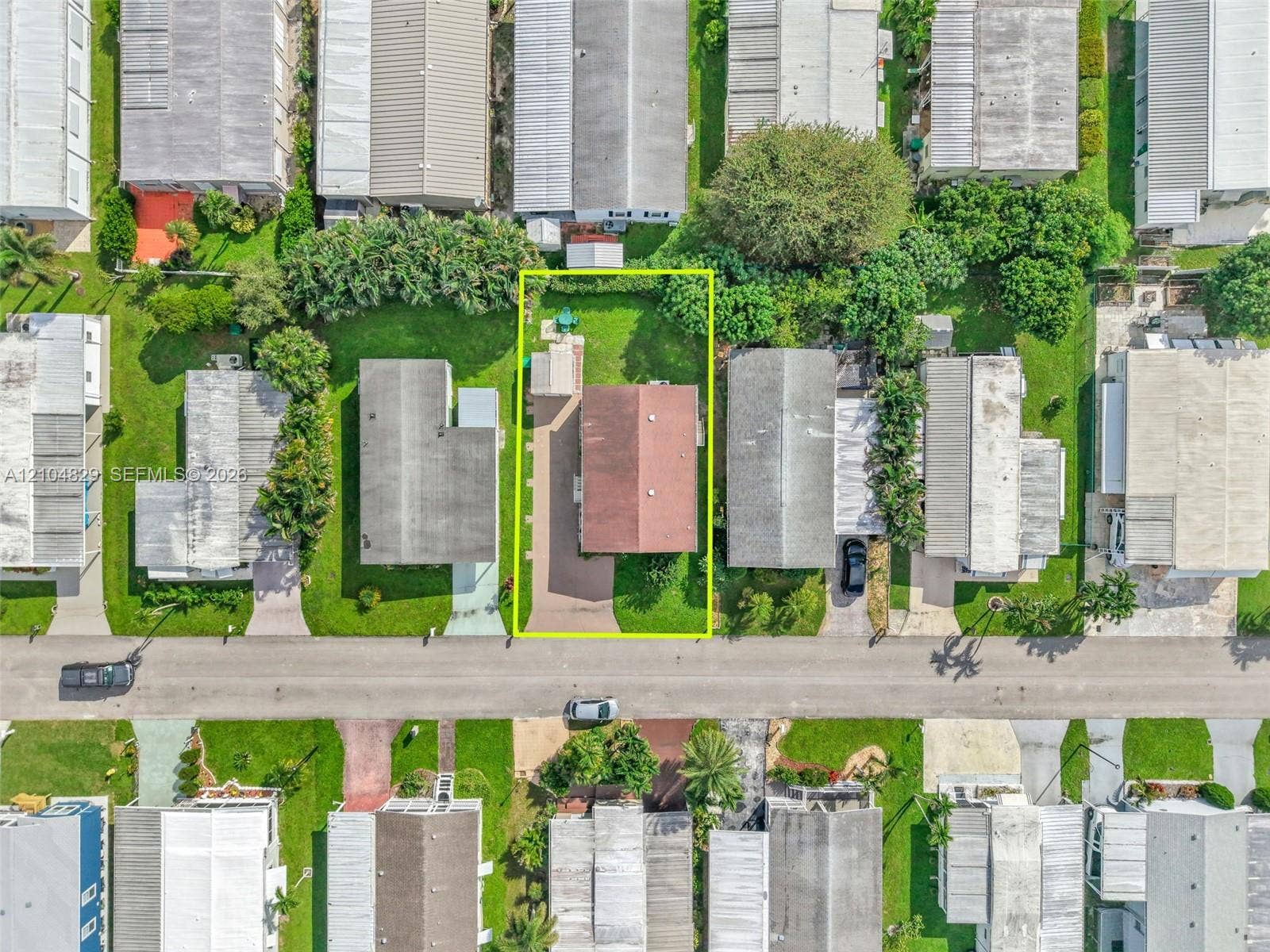 1880 SW 83rd Terrace, Davie, FL 33324 Aerial perspective of a property featuring a paved driveway, a detached storage structure, and a perimeter of mature landscaping
