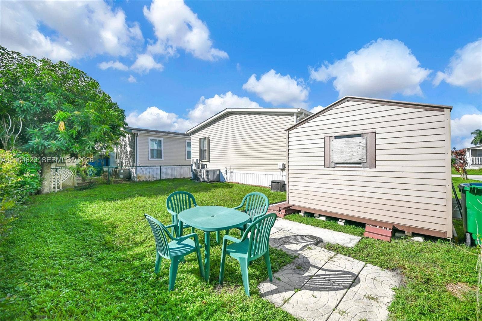 1880 SW 83rd Terrace, Davie, FL 33324 Exterior yard space featuring a manicured lawn, detached storage shed with horizontal siding, and a decorative concrete paver walkway