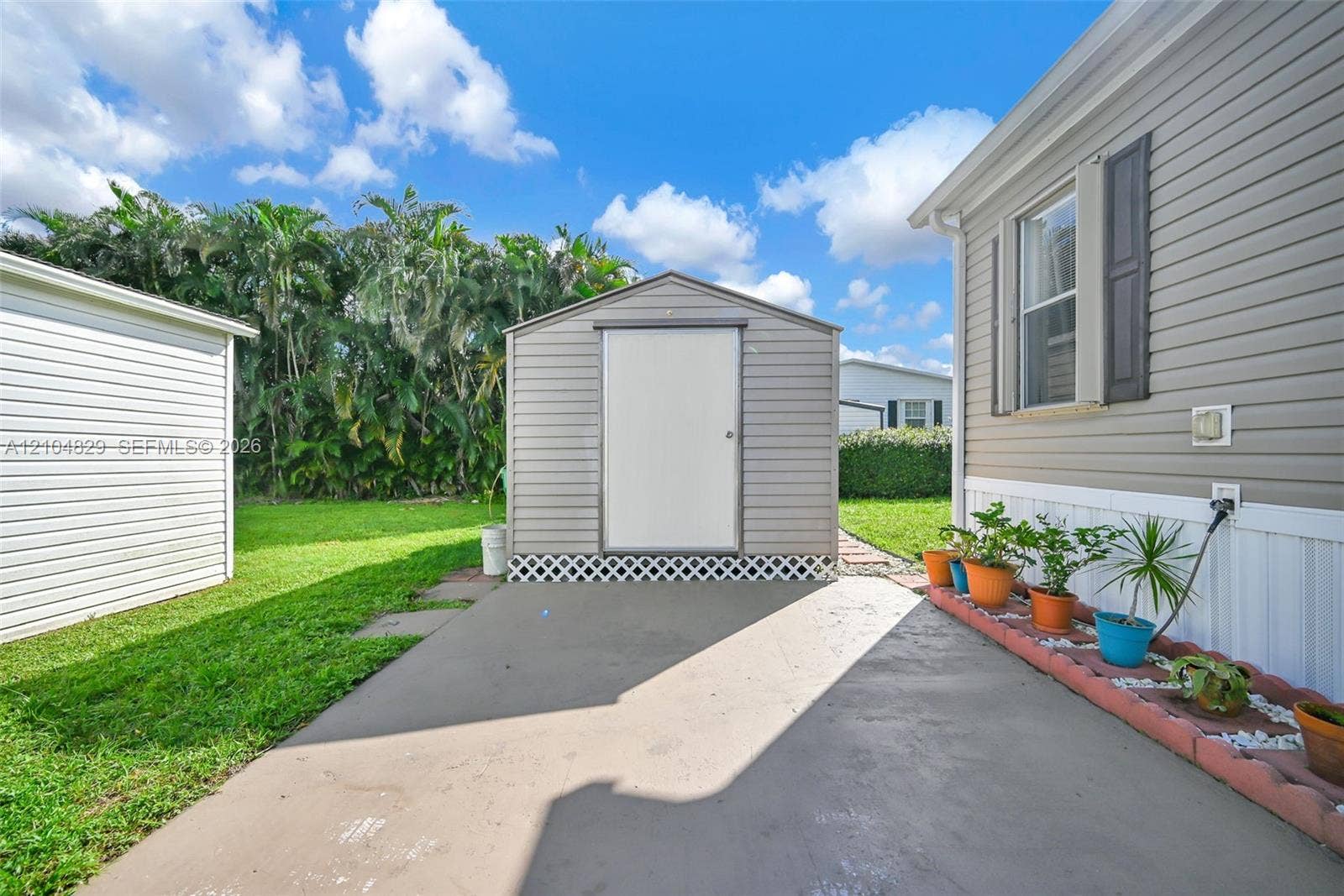 1880 SW 83rd Terrace, Davie, FL 33324 Exterior space featuring a concrete patio, a detached metal storage shed, and a raised concrete border planter