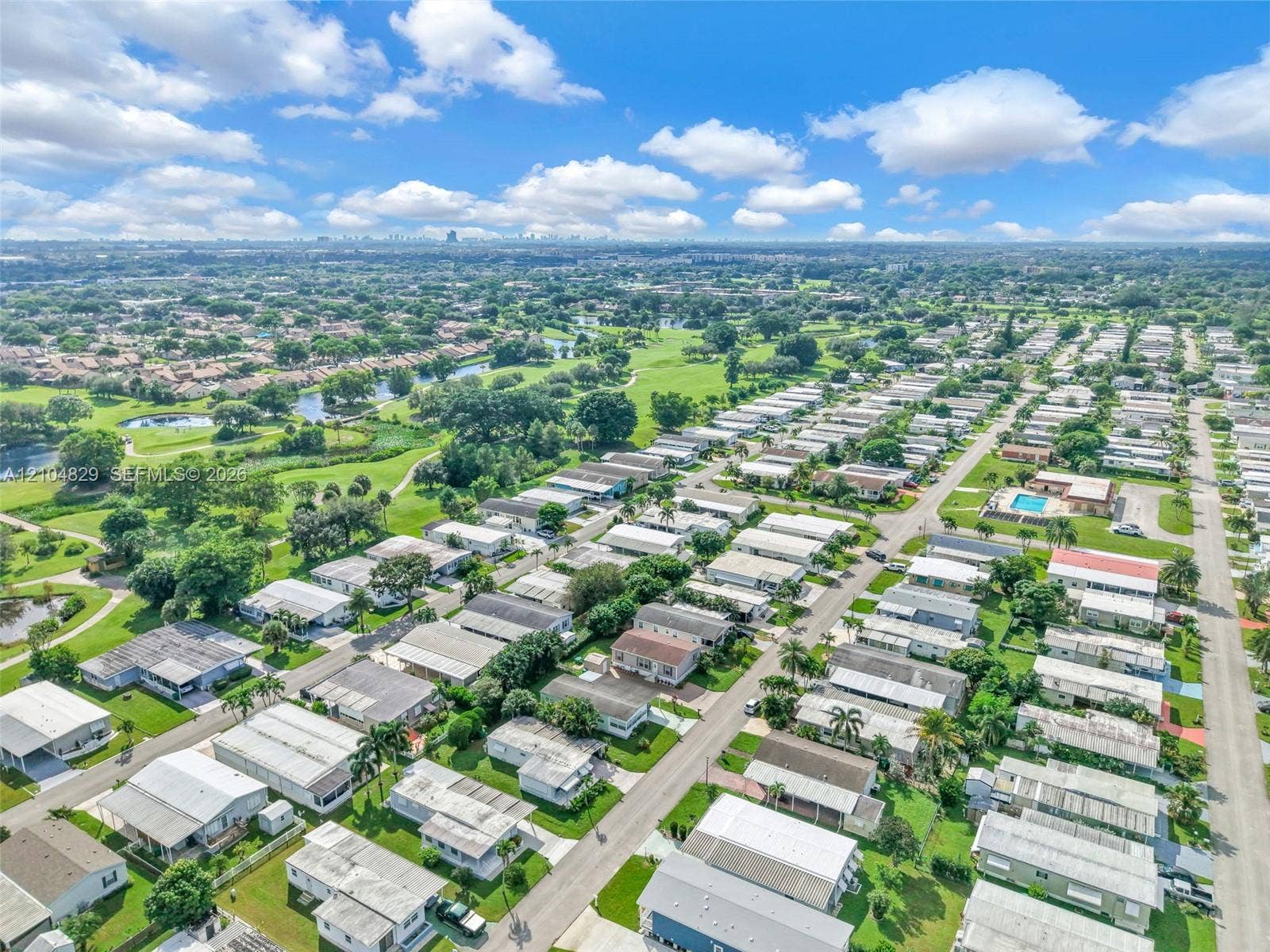 1880 SW 83rd Terrace, Davie, FL 33324 Aerial perspective featuring a residential community with paved streets, landscaped green spaces, established trees, and a central swimming pool
