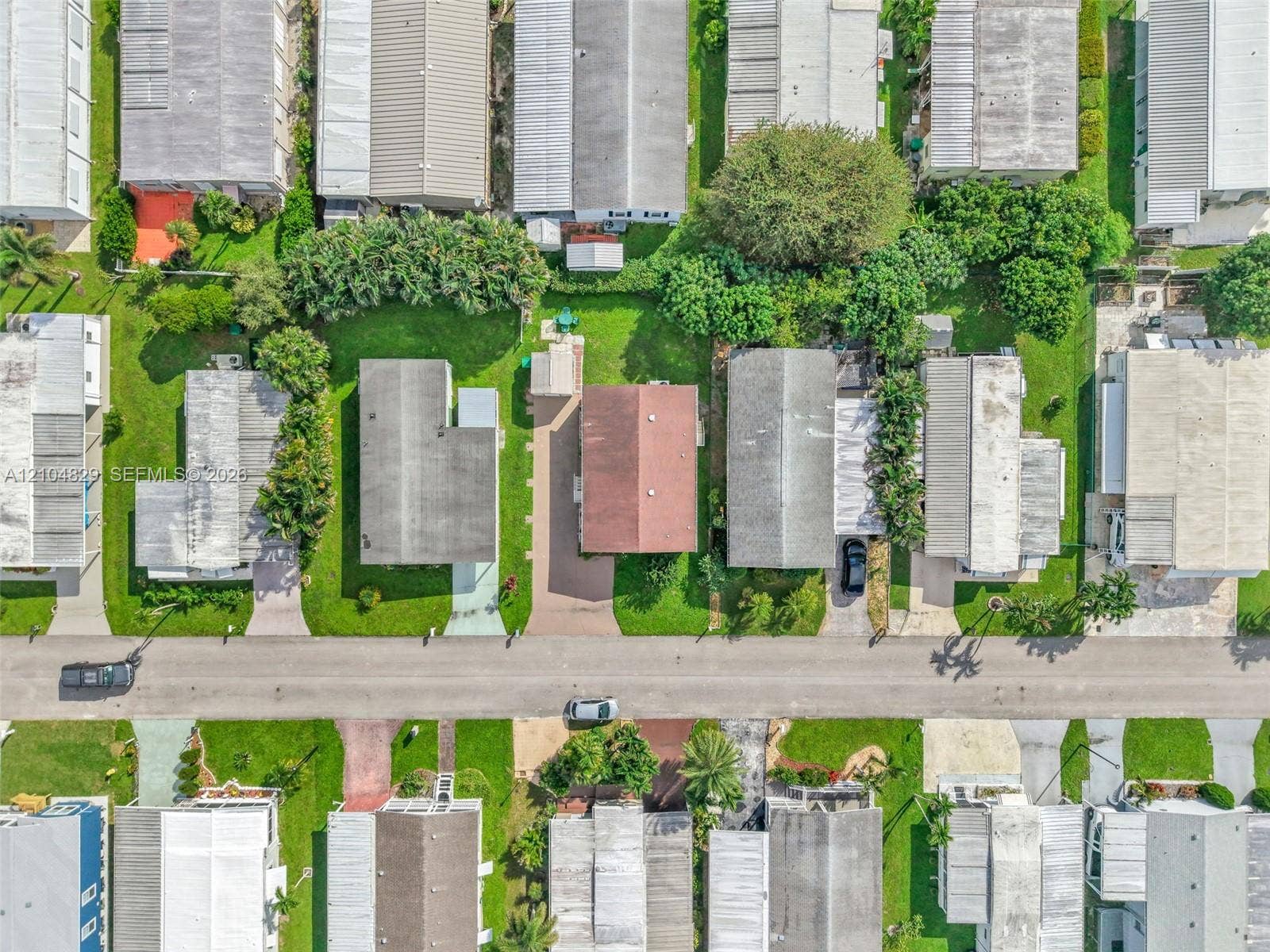 1880 SW 83rd Terrace, Davie, FL 33324 Aerial perspective of a residential lot featuring a paved driveway, mature landscaping, and grassy lawns