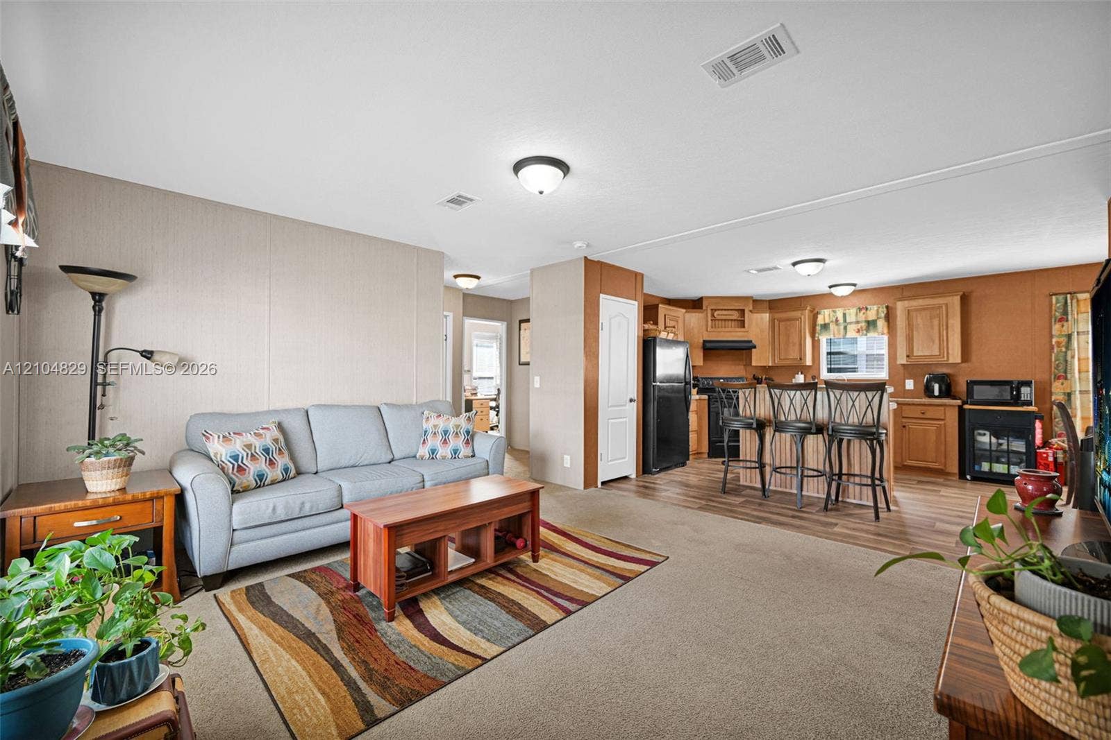 1880 SW 83rd Terrace, Davie, FL 33324 Open-concept interior featuring wood-finish flooring, natural wood cabinetry, flush-mount ceiling lighting, and a kitchen island with bar-style seating