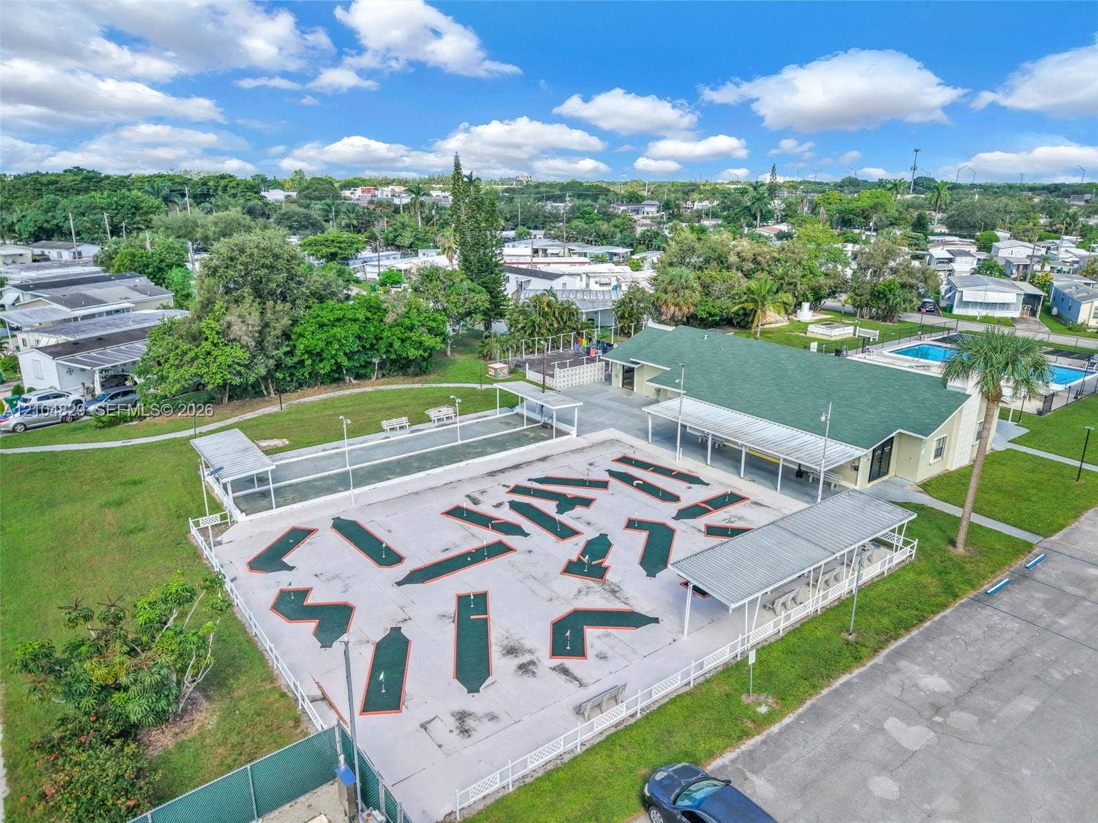 1880 SW 83rd Terrace, Davie, FL 33324 Community recreation area featuring a miniature golf course, bocce court with covered seating, swimming pool, and a clubhouse with a covered veranda