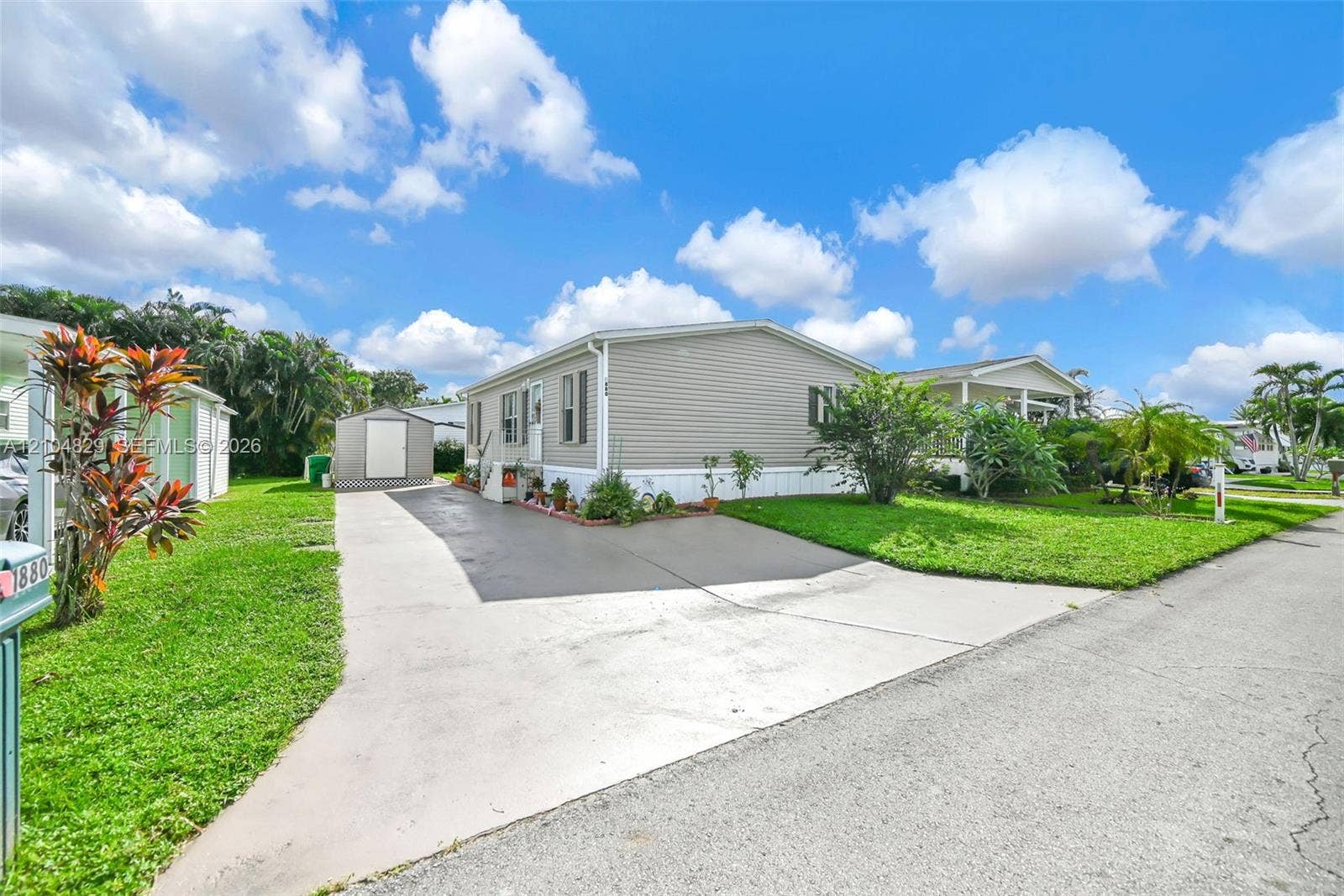 1880 SW 83rd Terrace, Davie, FL 33324 Single-story residence featuring light-toned horizontal siding, a concrete driveway, and an exterior storage shed situated on a manicured lawn