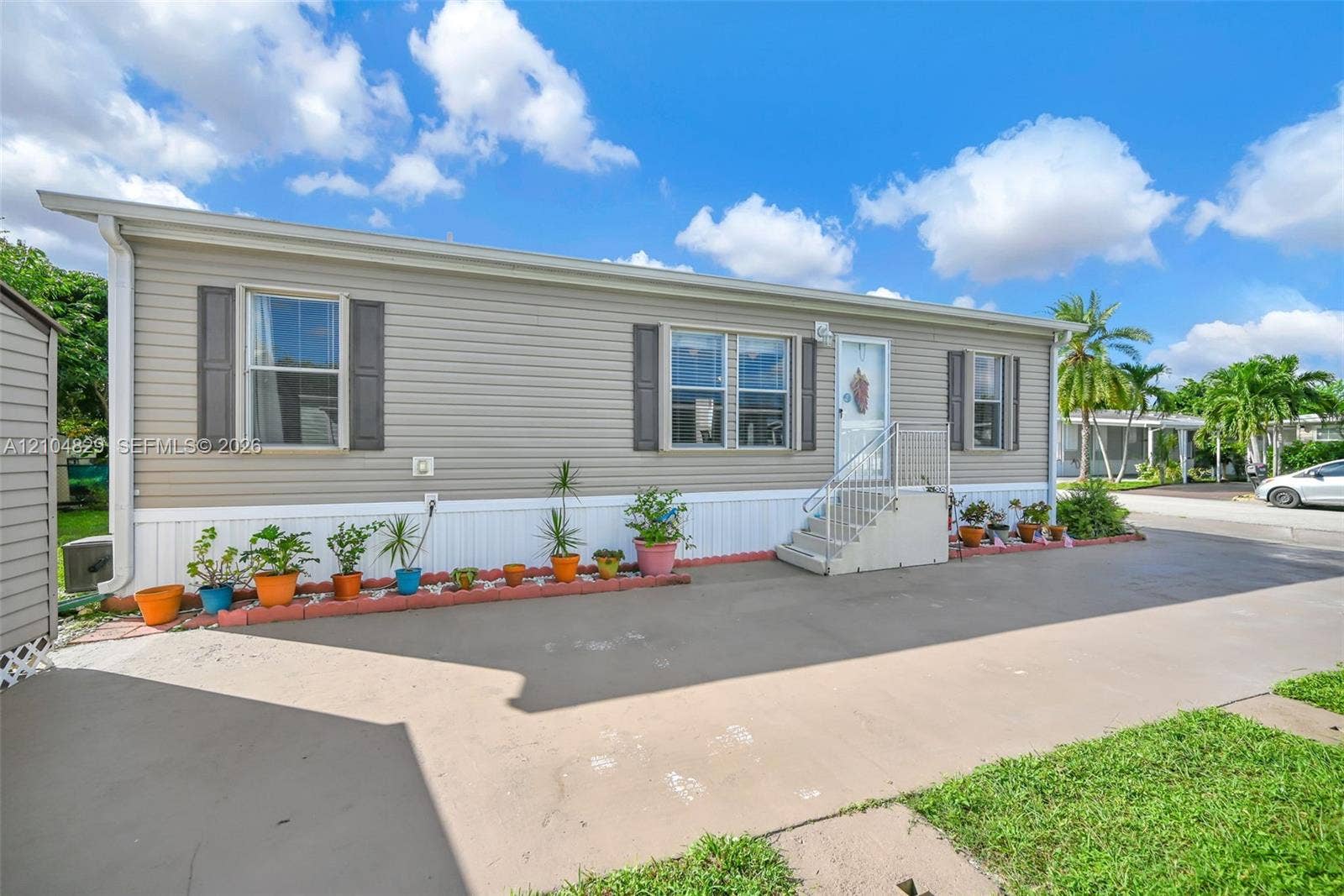 1880 SW 83rd Terrace, Davie, FL 33324 Exterior featuring horizontal siding, decorative shutters, concrete hardscaping, and metal stairs with railings