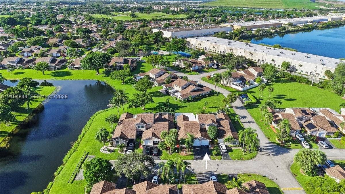 1216 NW 51st Way, Deerfield Beach, FL 33442 Aerial perspective of a multi-unit property featuring a shingled roof, asphalt driveway, and waterfront positioning
