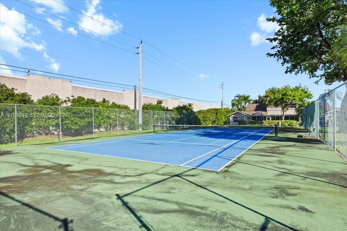 1216 NW 51st Way, Deerfield Beach, FL 33442 Tennis court featuring a high-tension chain-link perimeter fence and professional court surfacing