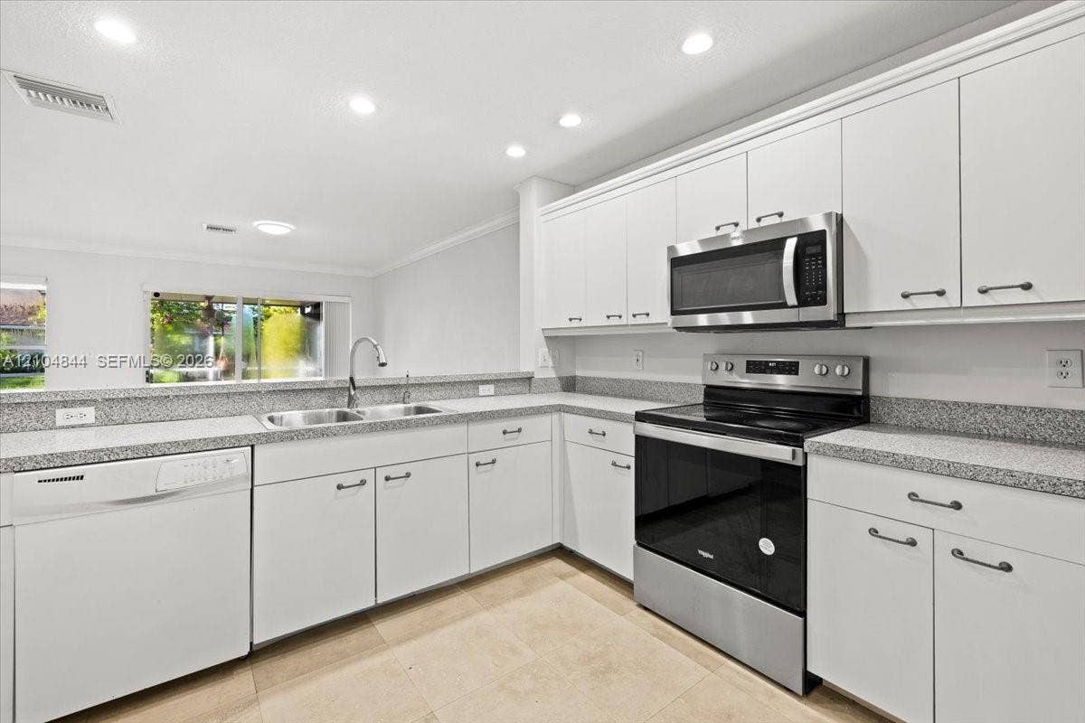 1216 NW 51st Way, Deerfield Beach, FL 33442 Kitchen featuring white cabinetry, stone-finish countertops, stainless steel appliances, recessed ceiling lighting, and tile flooring