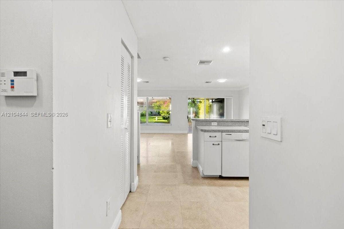 1216 NW 51st Way, Deerfield Beach, FL 33442 Interior space featuring large-format tile flooring, white cabinetry with stone-surface countertops, recessed lighting, and sliding glass doors