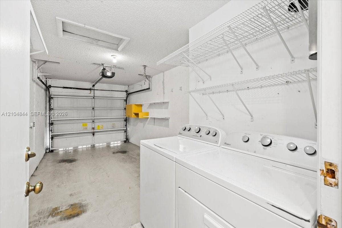 1216 NW 51st Way, Deerfield Beach, FL 33442 Enclosed garage featuring an automatic door opener, overhead lighting, wire shelving, and built-in laundry hookups