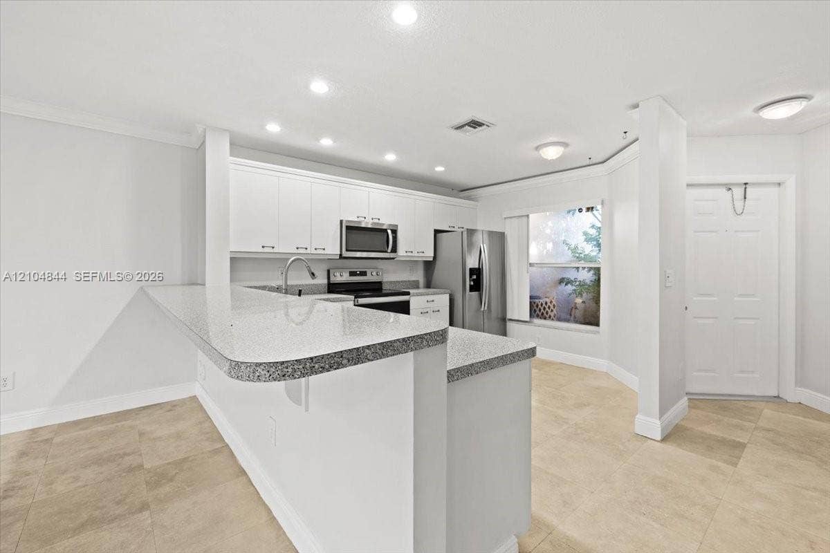 1216 NW 51st Way, Deerfield Beach, FL 33442 Kitchen featuring white cabinetry, speckled stone countertops, stainless steel appliances, and large-format tile flooring