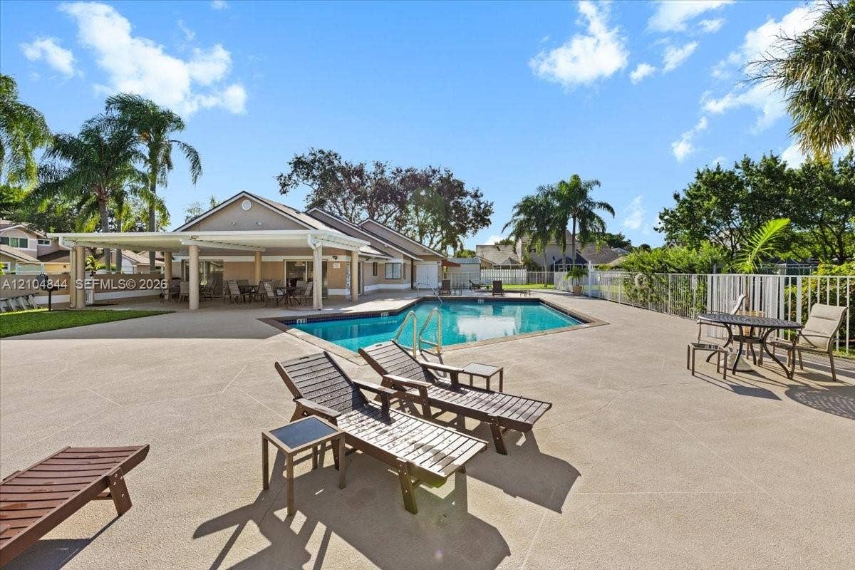 1216 NW 51st Way, Deerfield Beach, FL 33442 Outdoor pool with integrated metal railing, expansive concrete deck, and covered patio area