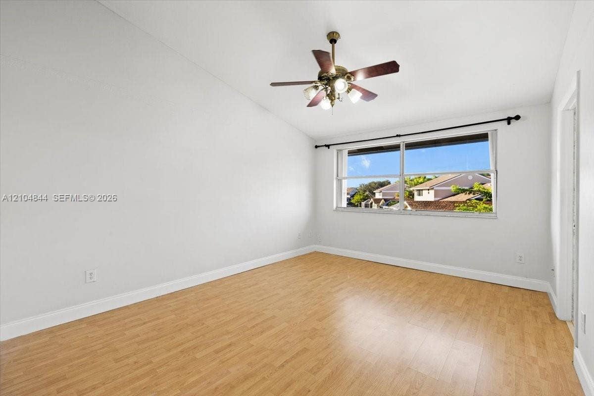 1216 NW 51st Way, Deerfield Beach, FL 33442 Room featuring vaulted ceilings, wood-finish flooring, a multi-blade ceiling fan with integrated lighting, and a horizontal window