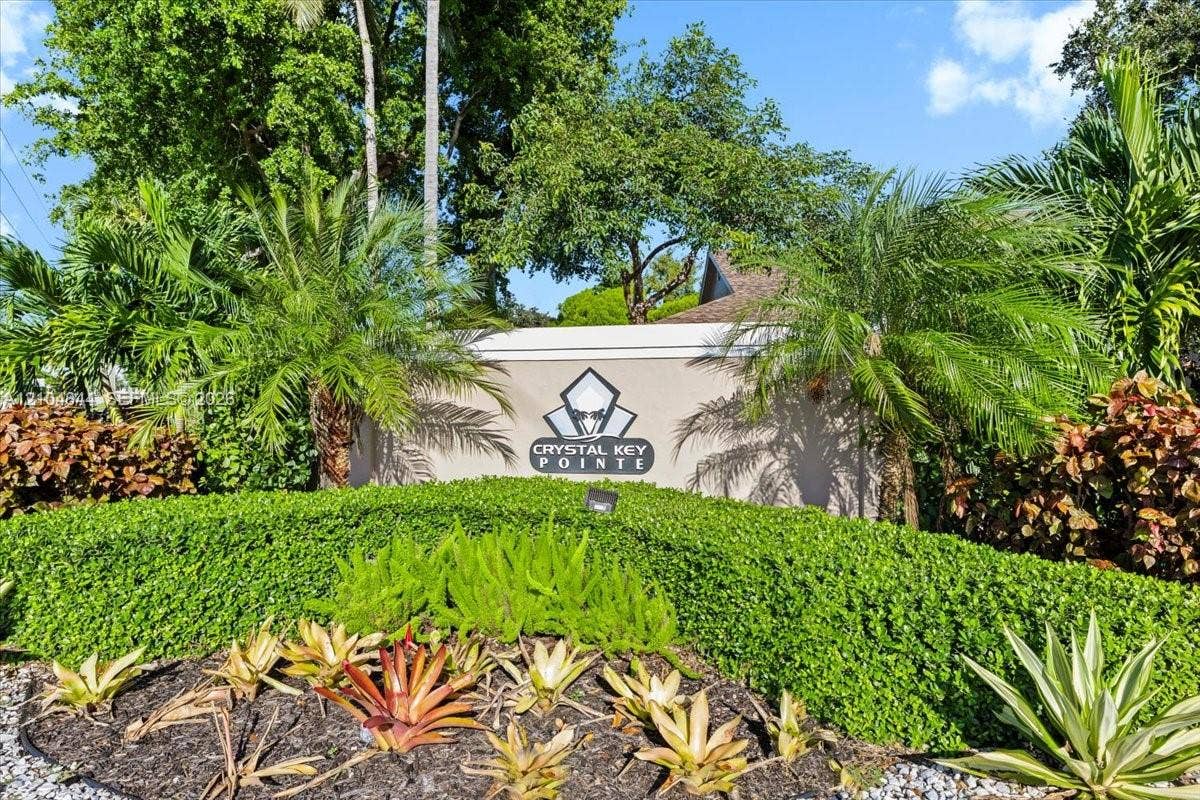 1216 NW 51st Way, Deerfield Beach, FL 33442 Community monument sign featuring professional landscaping, manicured hedges, and mature palm trees