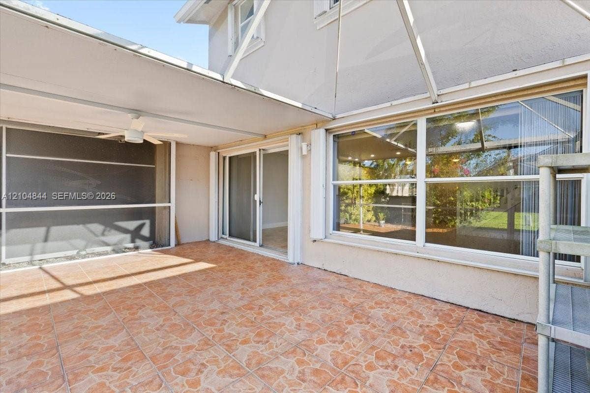 1216 NW 51st Way, Deerfield Beach, FL 33442 Screened-in patio featuring patterned ceramic tile flooring, a covered ceiling with an integrated fan, and oversized sliding glass doors