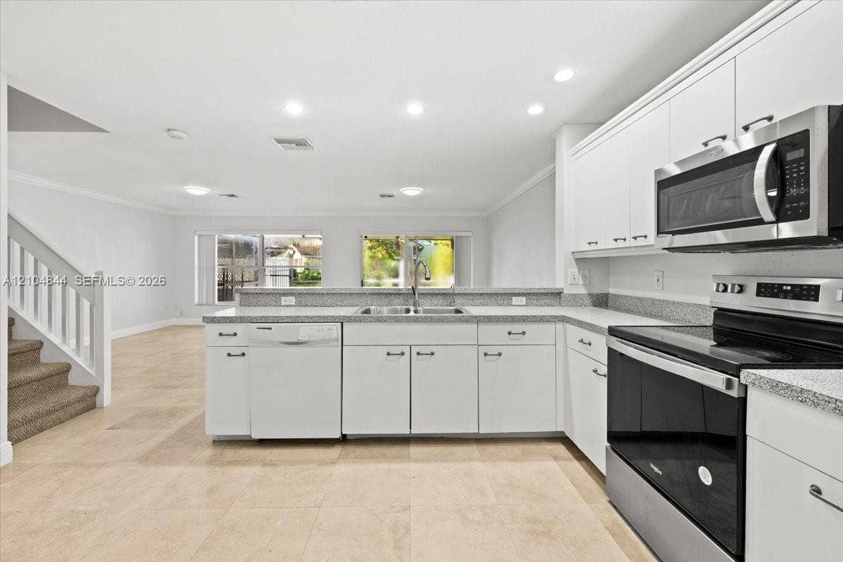 1216 NW 51st Way, Deerfield Beach, FL 33442 Kitchen featuring white cabinetry, stone-finish countertops, stainless steel appliances, recessed lighting, and tile flooring
