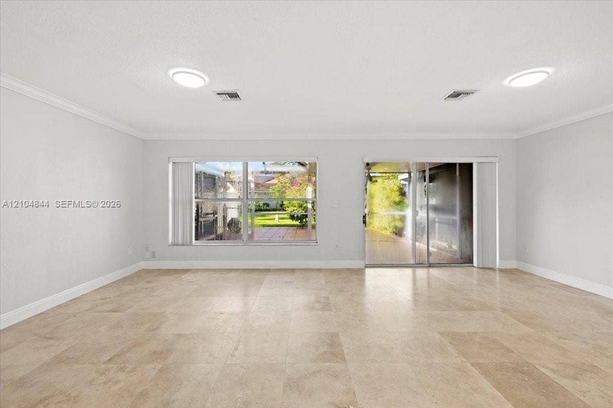 1216 NW 51st Way, Deerfield Beach, FL 33442 Neutral-toned tile flooring, recessed ceiling lighting, crown molding, expansive windows, and glass sliding door