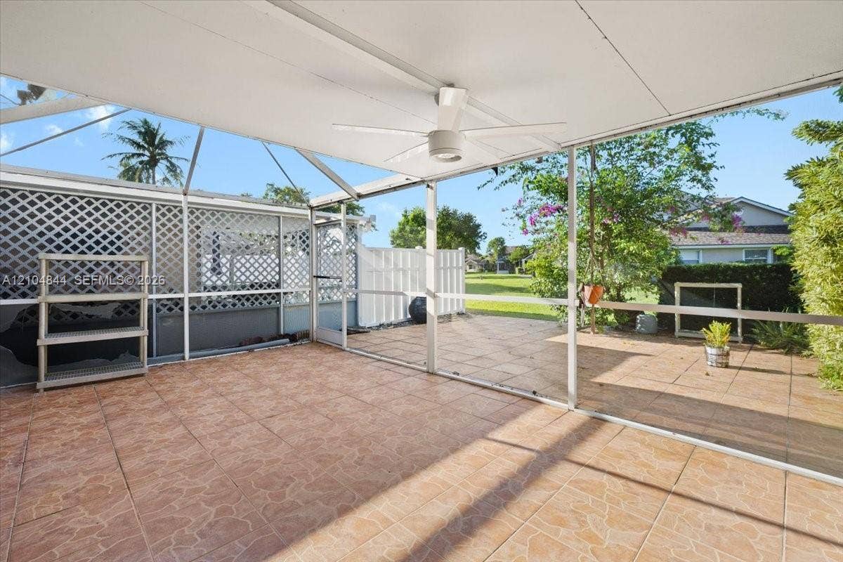 1216 NW 51st Way, Deerfield Beach, FL 33442 Screened-in patio featuring tiled flooring, a ceiling fan, and decorative lattice wall panels