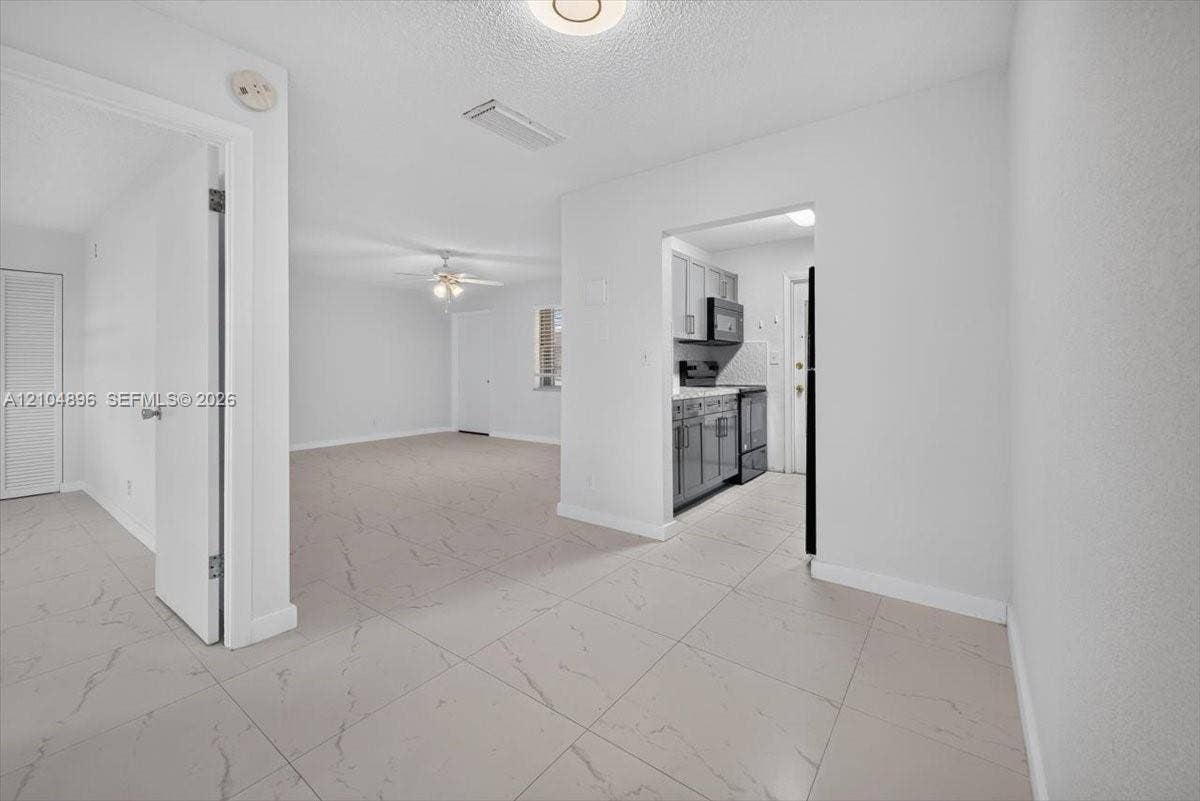 Large-format tile flooring with veining detail, recessed lighting, and a ceiling fan with integrated light fixture