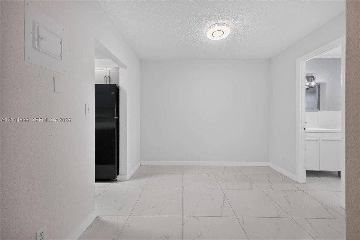 Large-format tile flooring with marble-pattern veining, flush-mount circular lighting fixture, and neutral wall finishes