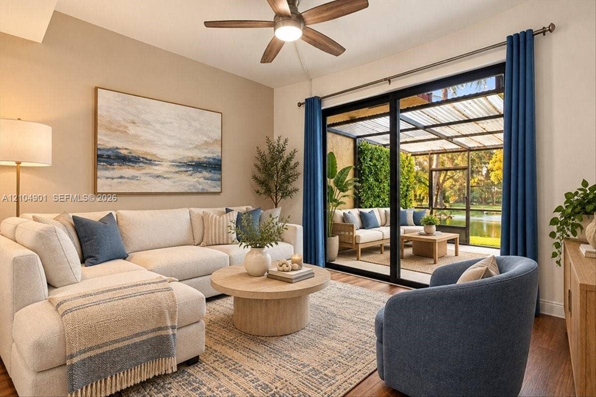 Black-framed sliding glass doors opening to a screened-in lanai, wood-finish flooring, and a ceiling fan with integrated lighting