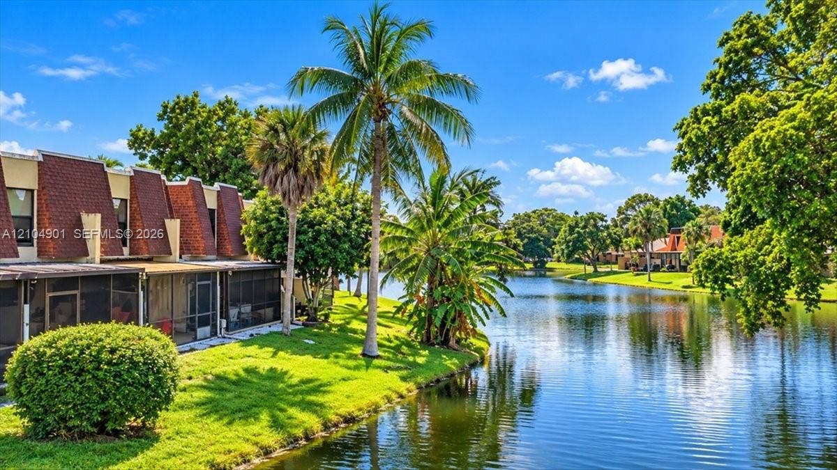 Waterfront property featuring screened-in patios, mature tropical landscaping, and shingle-style roof accents