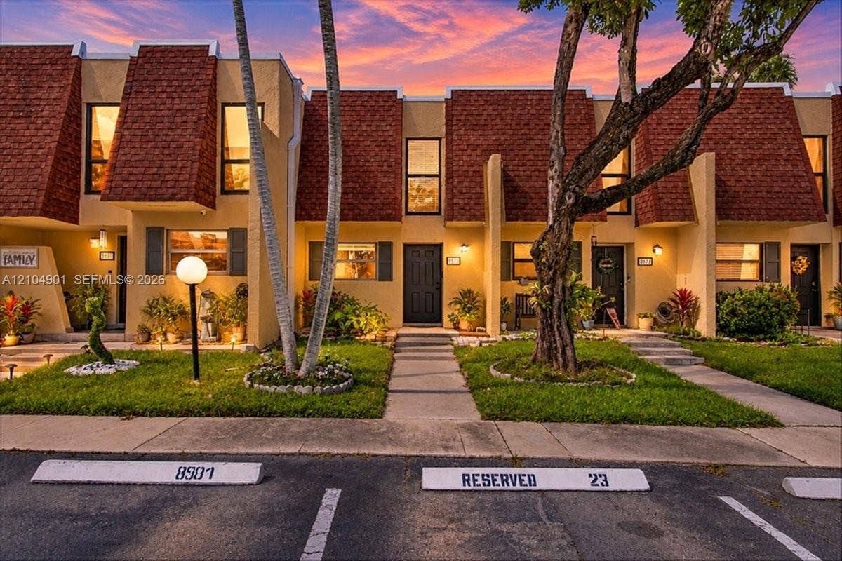 Multi-level exterior featuring mansard rooflines, stucco finish, concrete walkways, and designated parking spaces