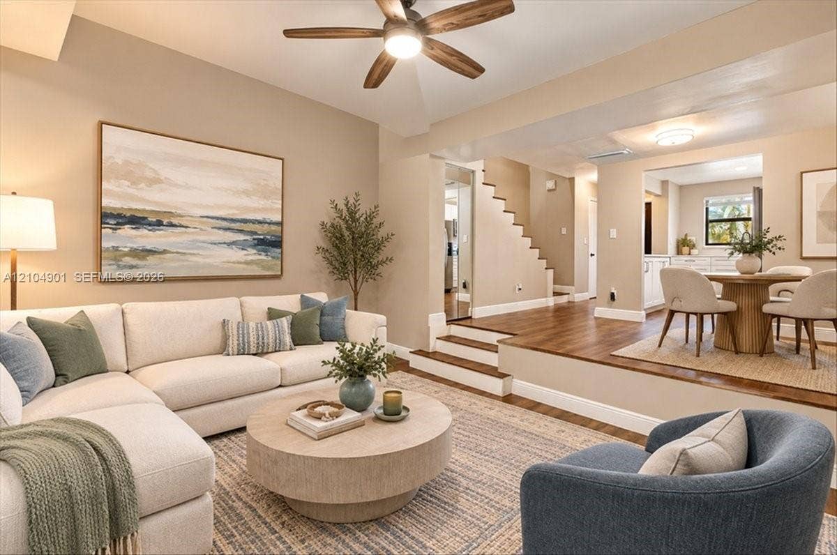 Sunken living area featuring wood-finish flooring, a neutral color palette, and an integrated ceiling fan with light fixture