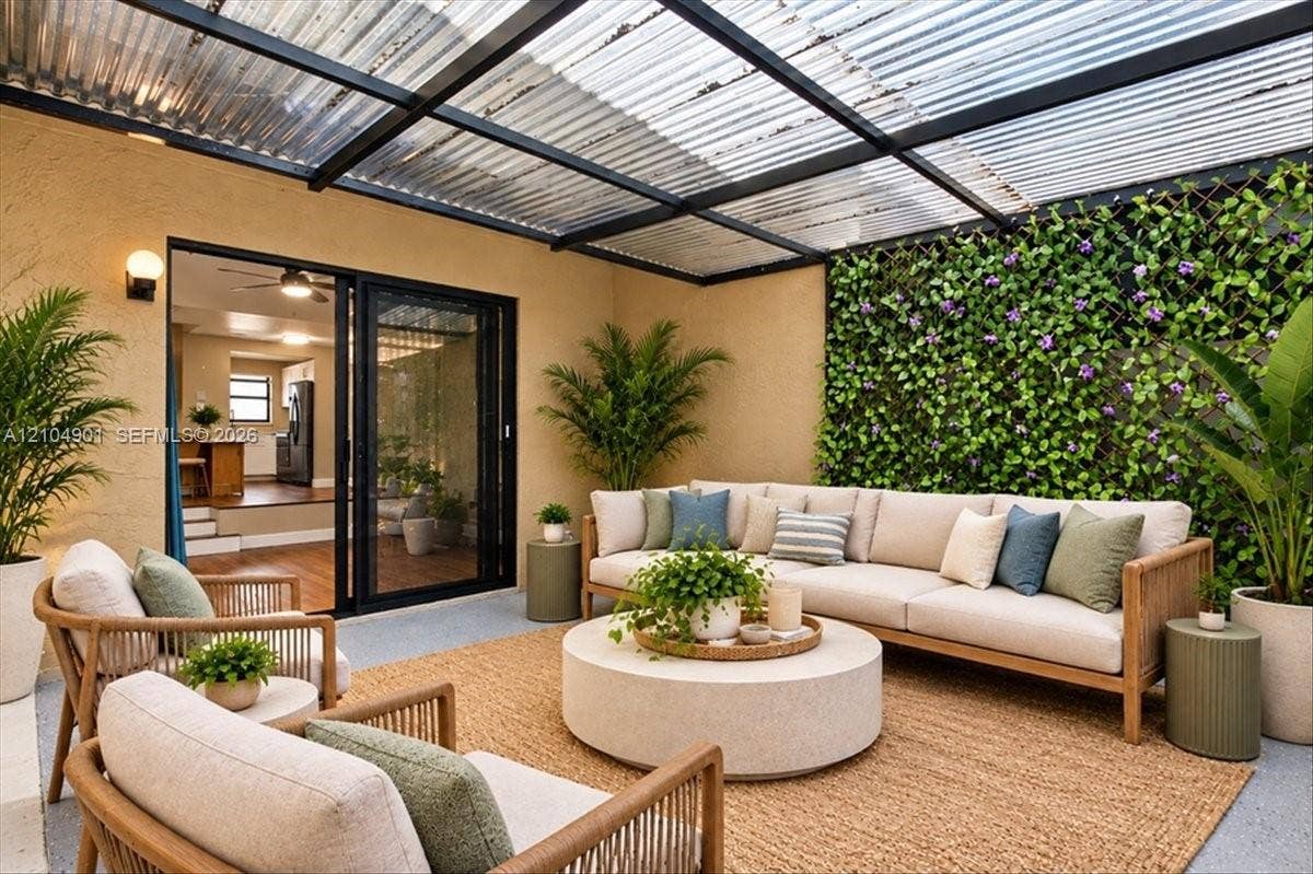 Covered patio featuring a translucent corrugated roof, black metal framework, exterior wall-mounted lighting, and a vertical lattice garden wall