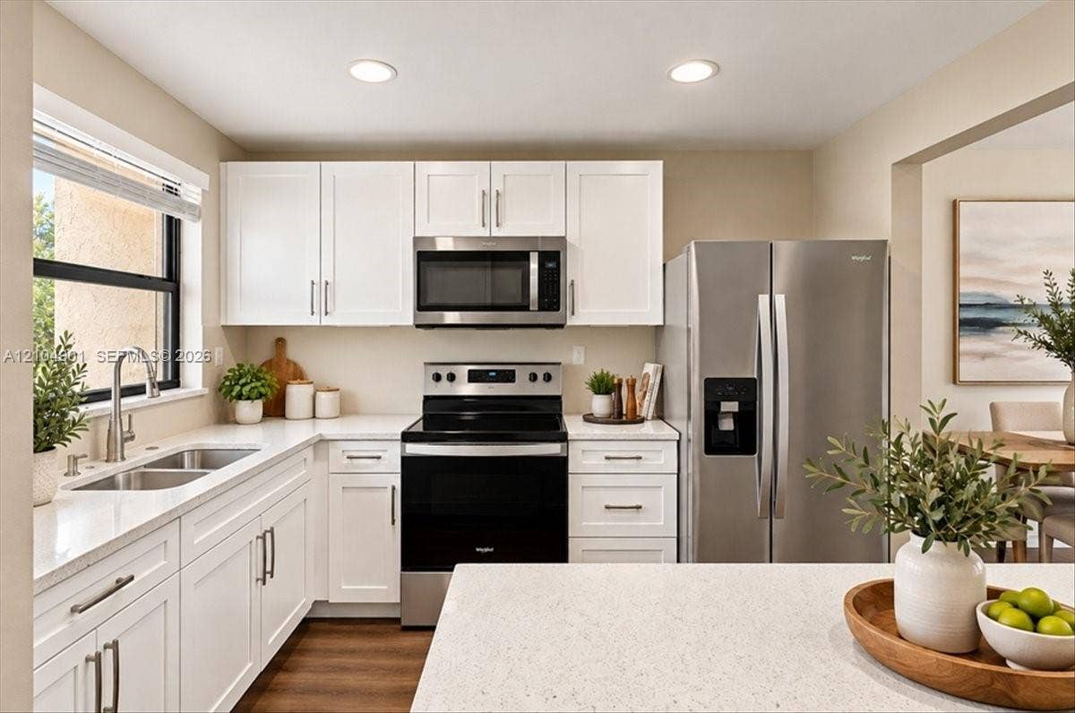 Kitchen featuring white Shaker-style cabinetry, quartz countertops, stainless steel appliances, a dual-basin undermount sink with a gooseneck faucet, and recessed lighting