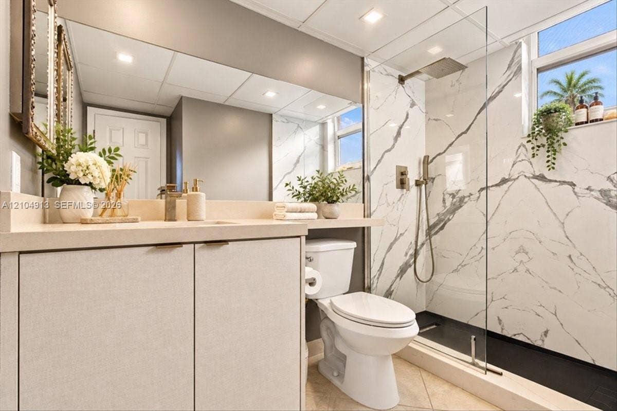 501 E Dania Beach Boulevard, #5-4A, Dania, Dania Beach, FL 33004 Bathroom featuring a walk-in shower with floor-to-ceiling stone-patterned tile, a glass partition, and a rainfall showerhead