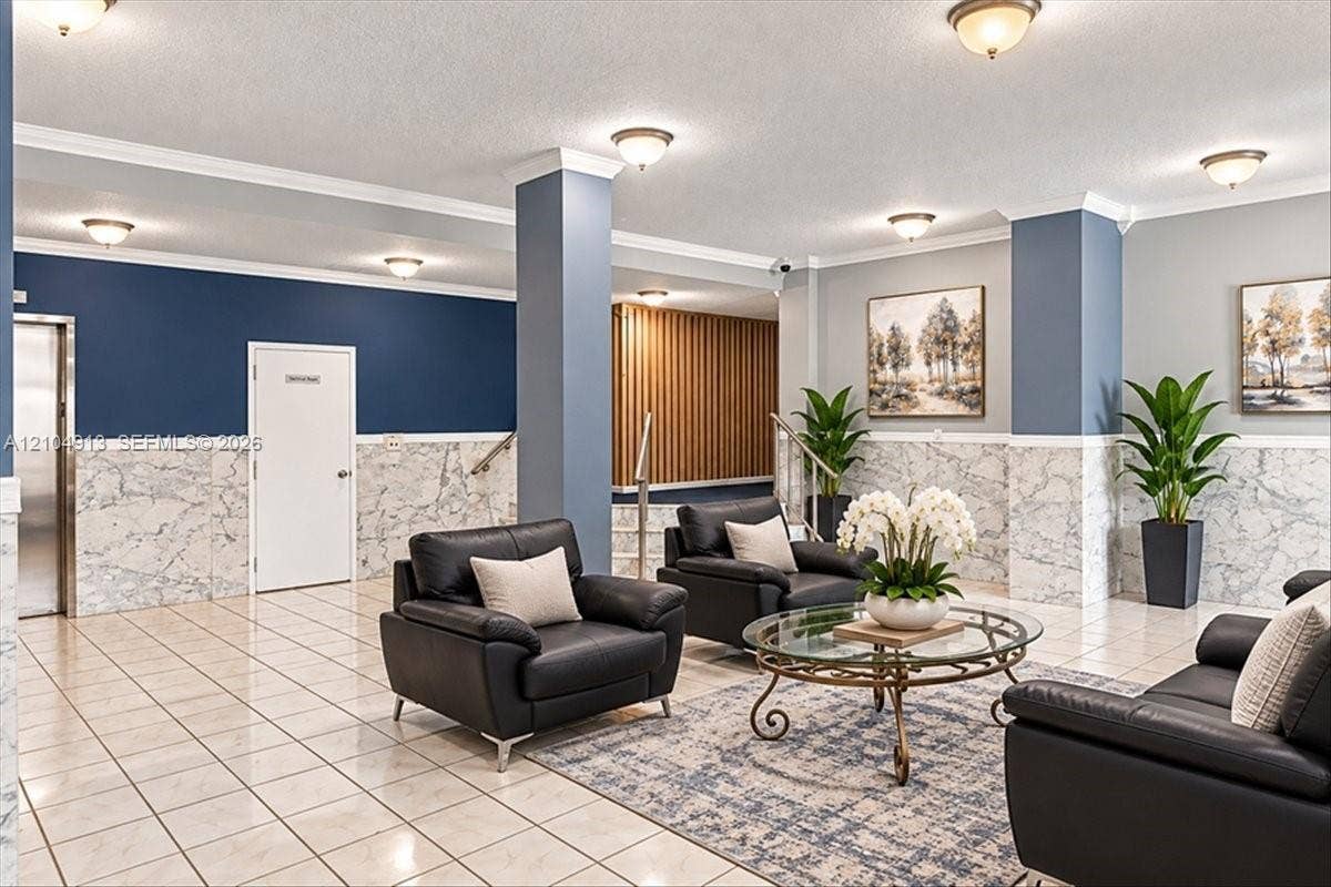 501 E Dania Beach Boulevard, #5-4A, Dania, Dania Beach, FL 33004 Building lobby featuring polished tile flooring, stone-patterned wainscoting, crown molding, built-in structural columns, and recessed lighting