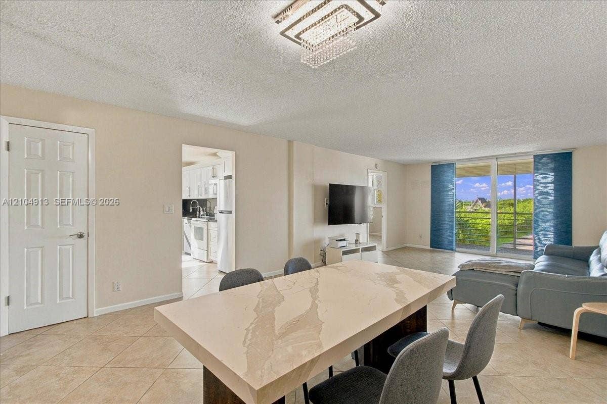501 E Dania Beach Boulevard, #5-4A, Dania, Dania Beach, FL 33004 Living space featuring tile flooring, a geometric crystal-style chandelier, and large sliding glass doors providing natural light