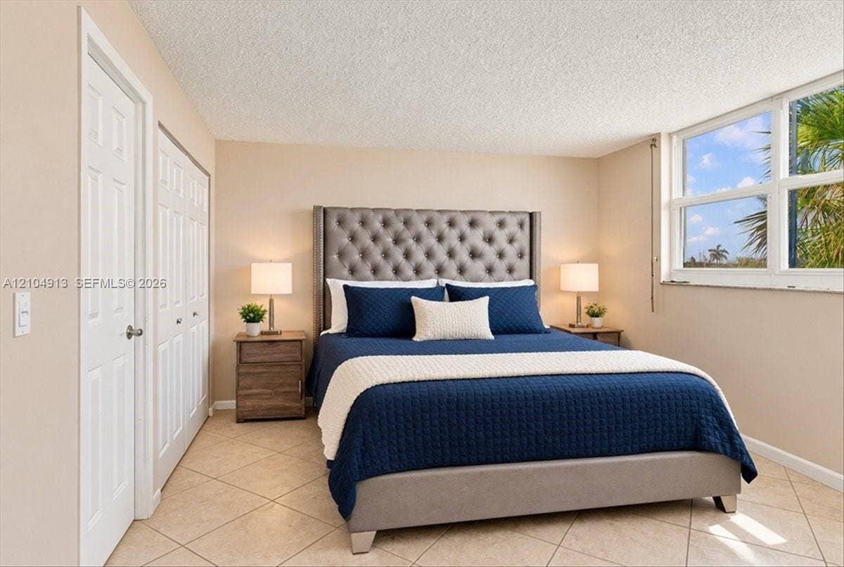 501 E Dania Beach Boulevard, #5-4A, Dania, Dania Beach, FL 33004 Bedroom featuring neutral wall paint, tile flooring, multi-pane window, and dual sliding closet doors