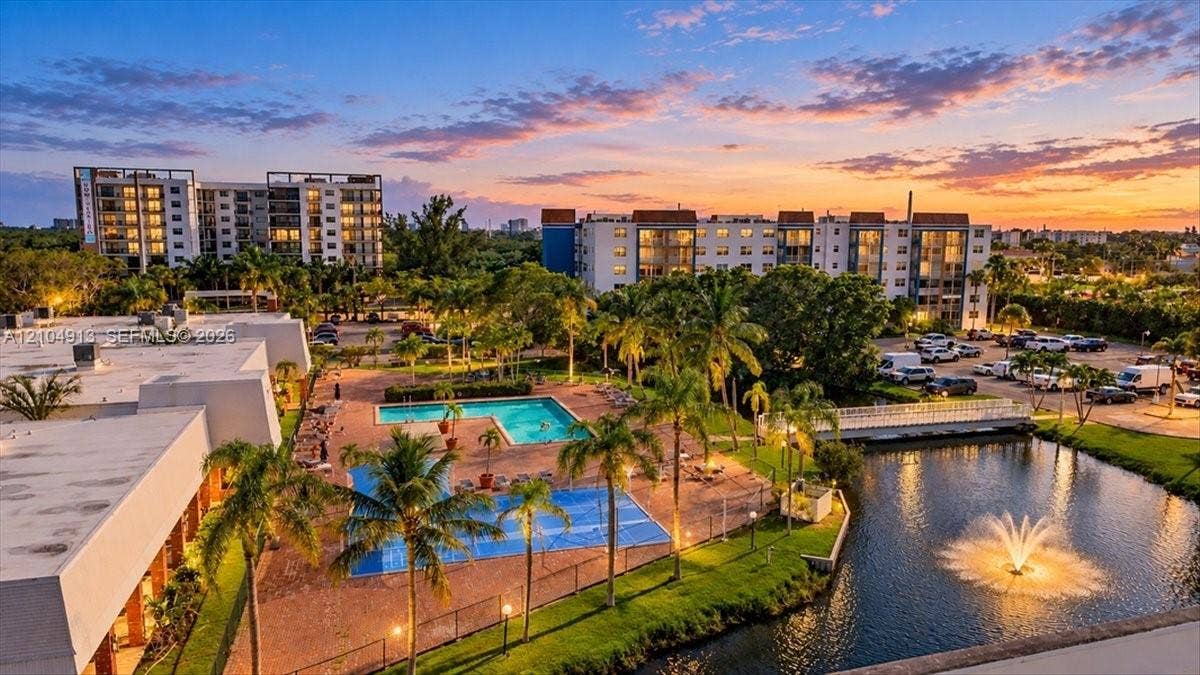 501 E Dania Beach Boulevard, #5-4A, Dania, Dania Beach, FL 33004 Outdoor swimming pool featuring a paved deck, surrounding palm trees, an aerating water fountain, and an adjacent pond
